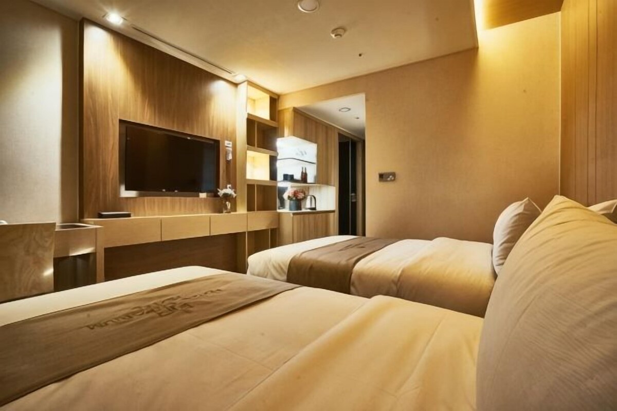 Une chambre d’hôtel avec deux lits, une télévision, un bureau et une kitchenette.