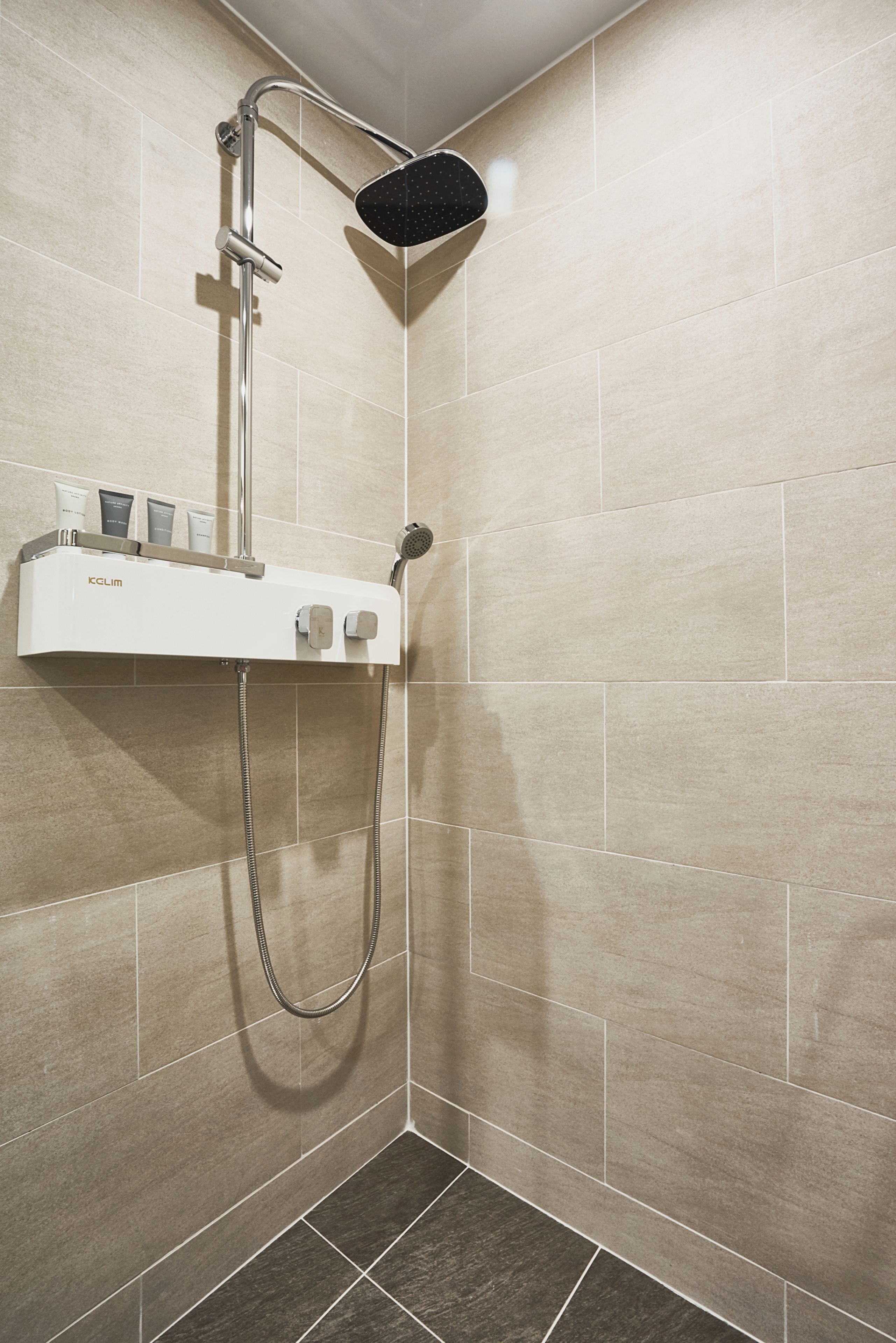 A modern shower with a handheld showerhead, a wall-mounted control panel, and a handheld shower attachment.