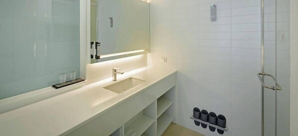 Une salle de bain moderne avec un lavabo blanc, un miroir et une douche.