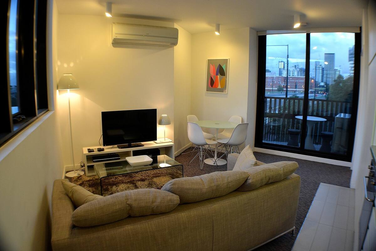 Een woonkamer met een bank, televisie en een eethoek.