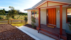 Een modern huis met een houten terras, een voordeur en een kleine veranda.