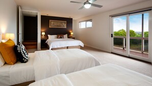 Een hotelkamer met twee bedden, een plafondventilator, een groot raam met uitzicht en een deur naar een balkon.