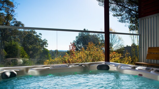 A hot tub with a clear view of trees and a wooden deck. - Artemis Retreat (Daylesford)