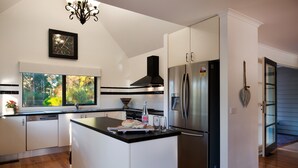 A modern kitchen with a central island, stainless steel appliances, and a view of the outdoors. - Artemis Retreat (Daylesford)