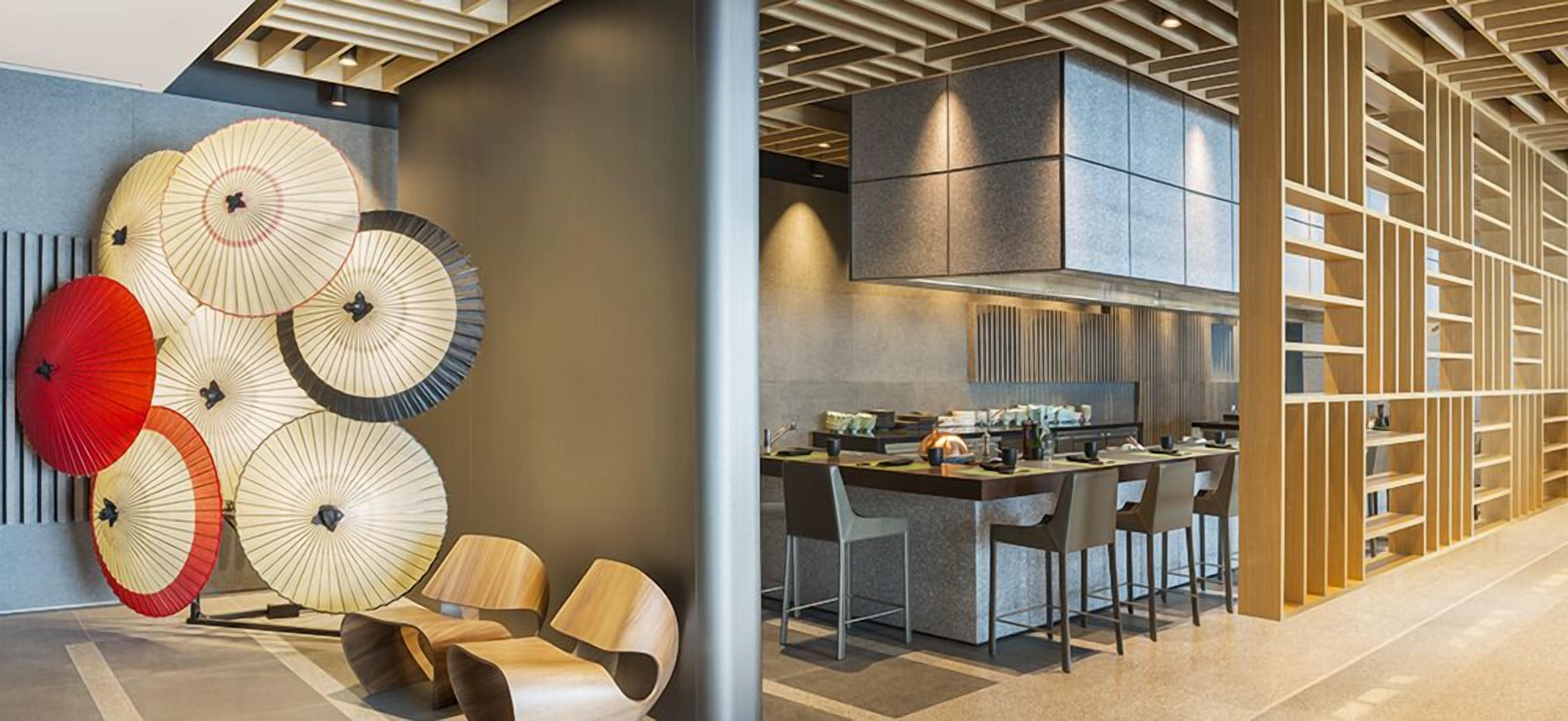 A modern kitchen with a central island, a dining area with chairs, and a decorative wall with umbrellas.
