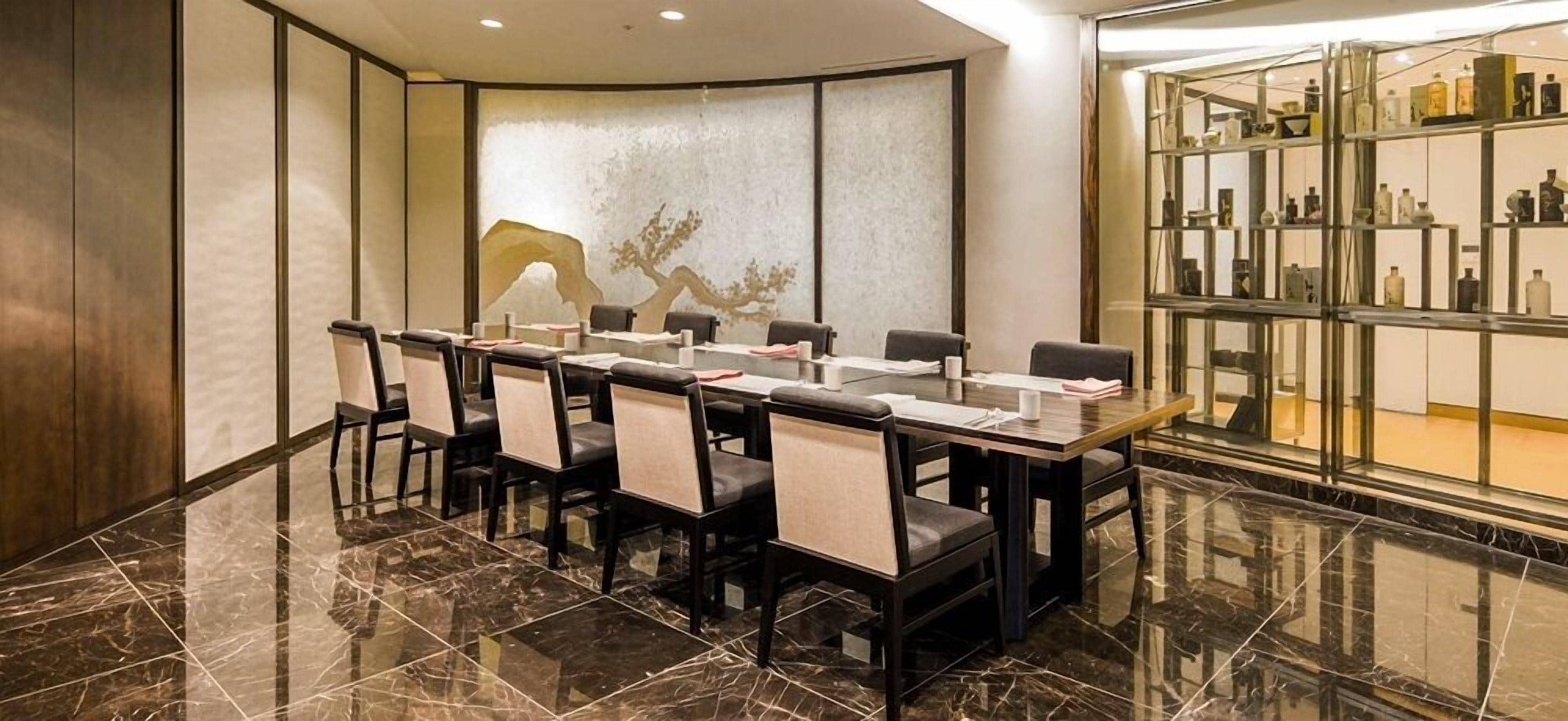 Un salón de conferencias con una larga mesa, sillas y una pared decorativa.