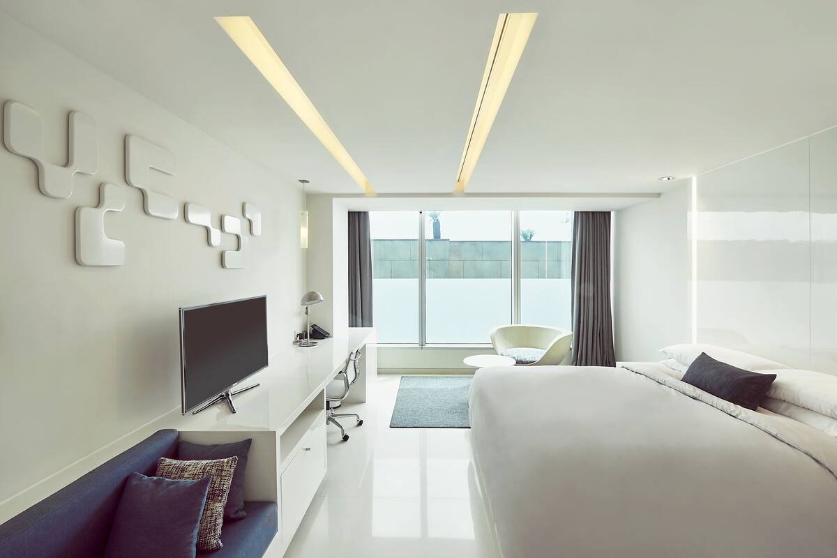 Een moderne hotelkamer met een groot bed, een bank, een televisie en uitzicht op de stad.