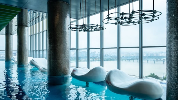 Una piscina interior con amplios ventanales, iluminación moderna y asientos originales.