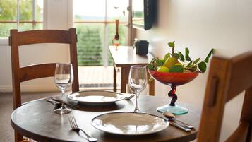 A dining table set with plates, cutlery, and glasses, with a bowl of fruit on the table.