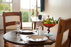 A dining table set with plates, cutlery, and glasses, with a bowl of fruit on the table. - Daylesford House Studio (Daylesford)