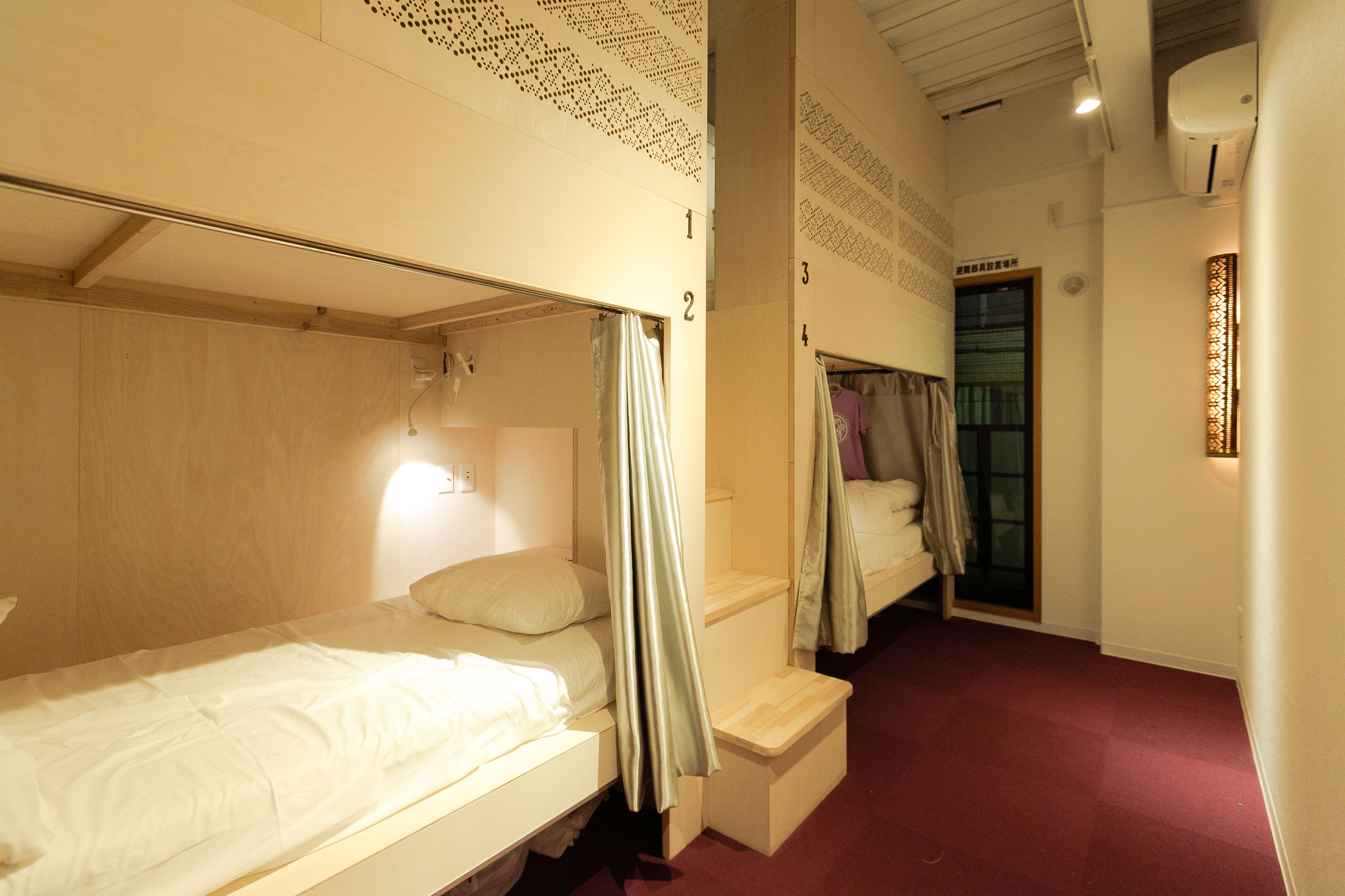 A hotel room with bunk beds, a small desk, and a window with curtains.