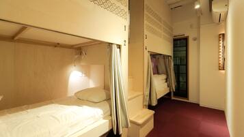 A hotel room with bunk beds, a small desk, and a window with curtains.