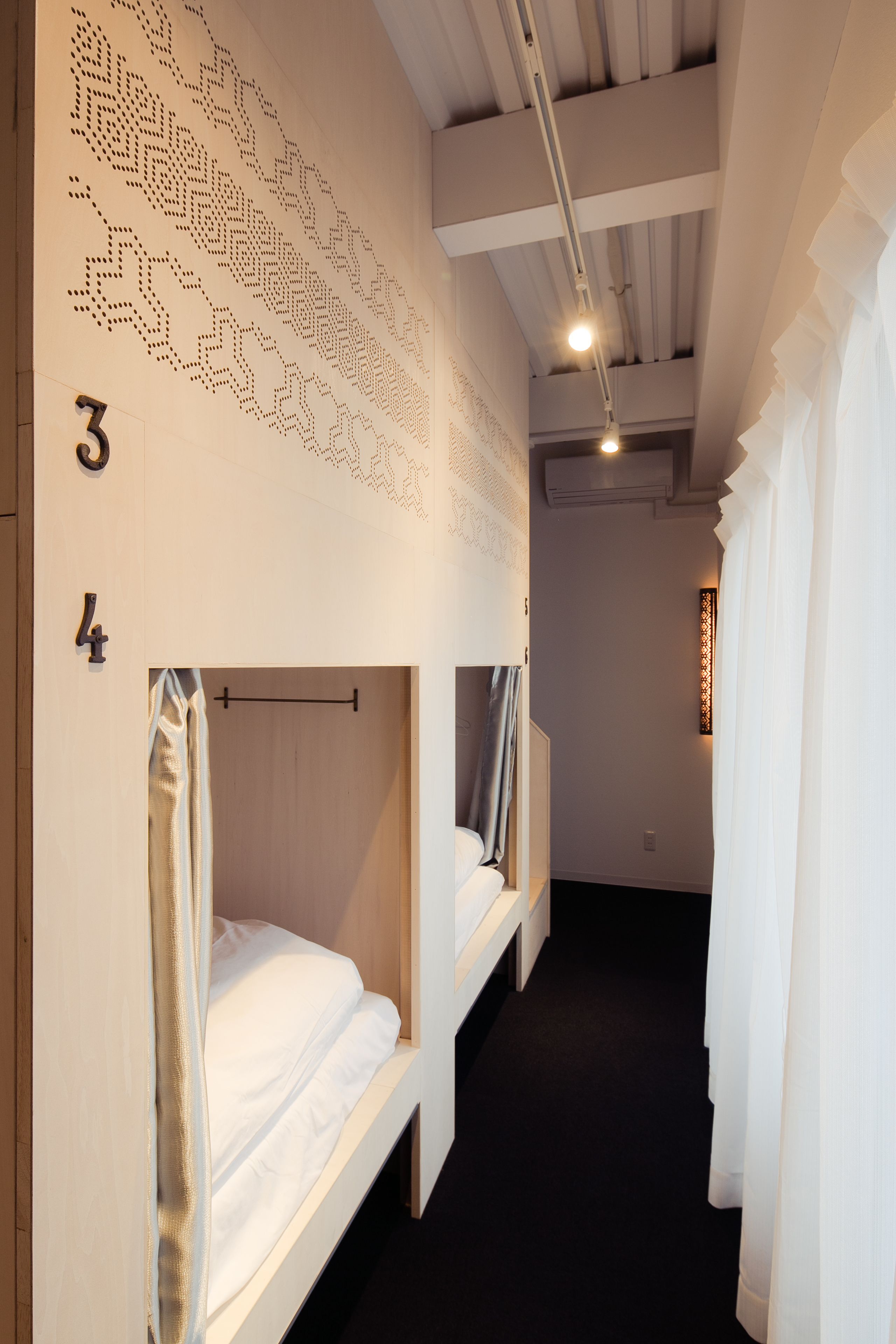 A narrow hallway with bunk beds, numbered 3 and 4, and a patterned wall design.