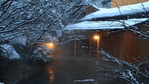 Een houten chalet met een sneeuwbedekte dak en een verlicht interieur.