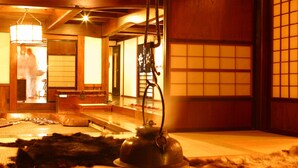 Een traditionele Japanse kamer met tatami vloerbedekking, een lage tafel met een waterkoker en een schuifdeur met een rasterpatroon.