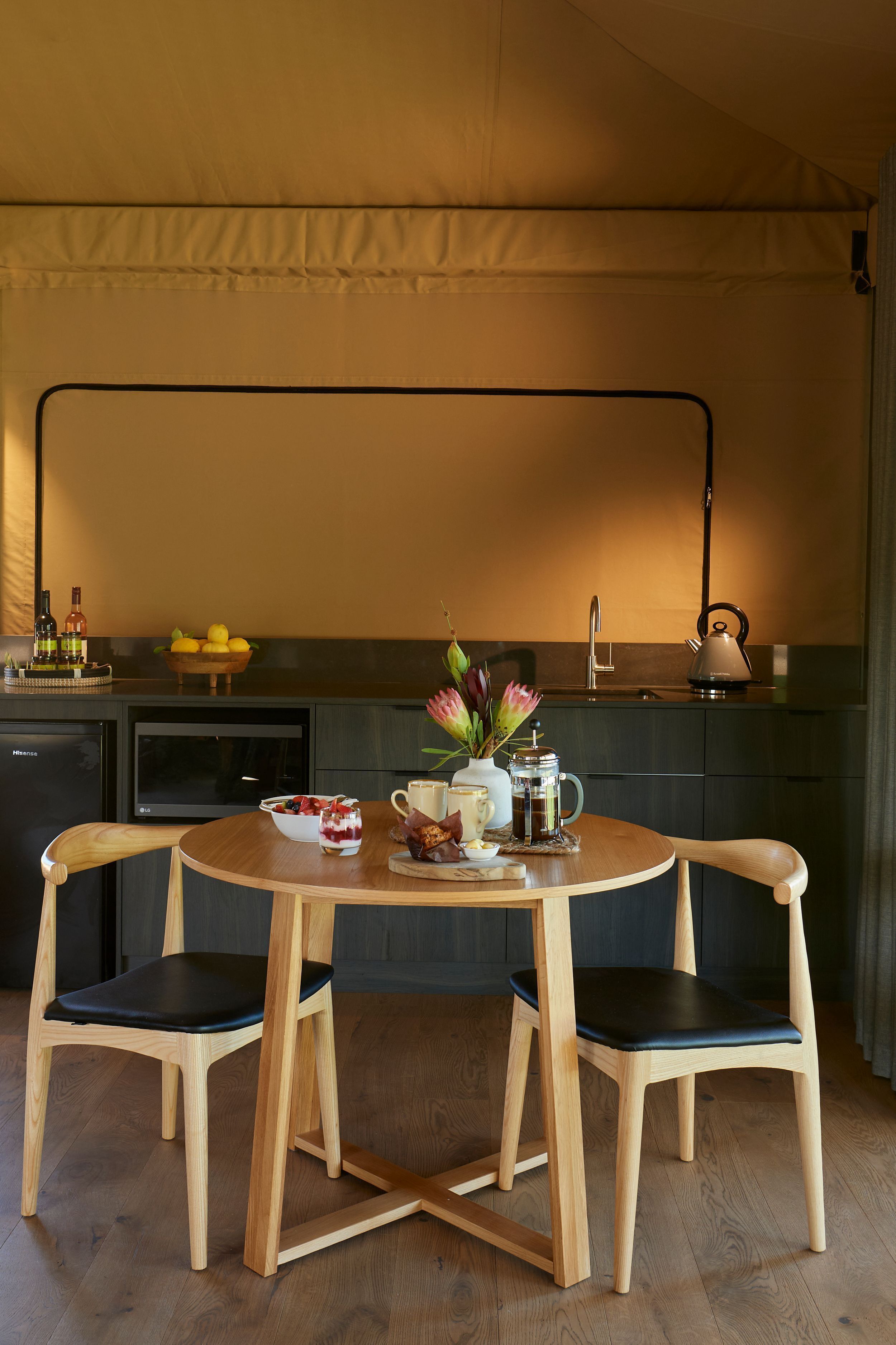 Una cucina compatta con zona pranzo, dotata di bollitore, una ciotola di frutta e macchina da caffè.