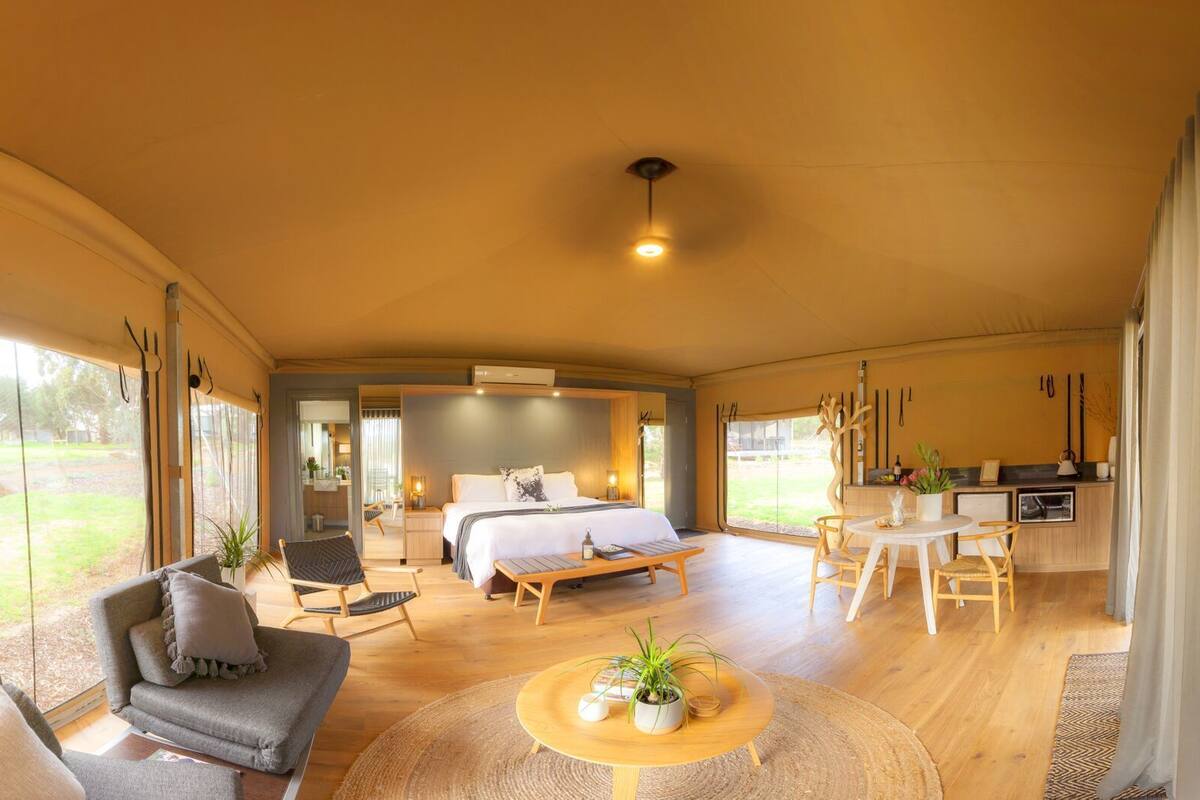 Quarto amplo com cama, mesa de jantar e cadeiras. Possui uma pequena cozinha com pia e geladeira.