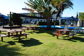 Ein Außenbereich mit Picknicktischen, einem Pool und einem Gebäude im Hintergrund.
