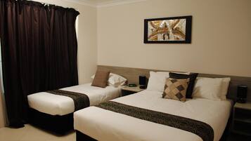 A hotel room with two beds, a nightstand, a clock, and a framed picture on the wall.