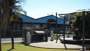 A building with a blue roof and a barbecue area with a grill and gas cylinders. - The David Motel (Berserker)