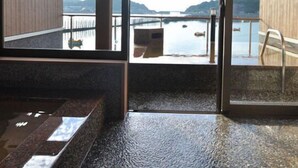 Un interior moderno con ventanas amplias que ofrecen vistas a una masa de agua y colinas lejanas.