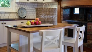 A kitchen with white cabinets, a wooden table, and a wicker basket with apples.