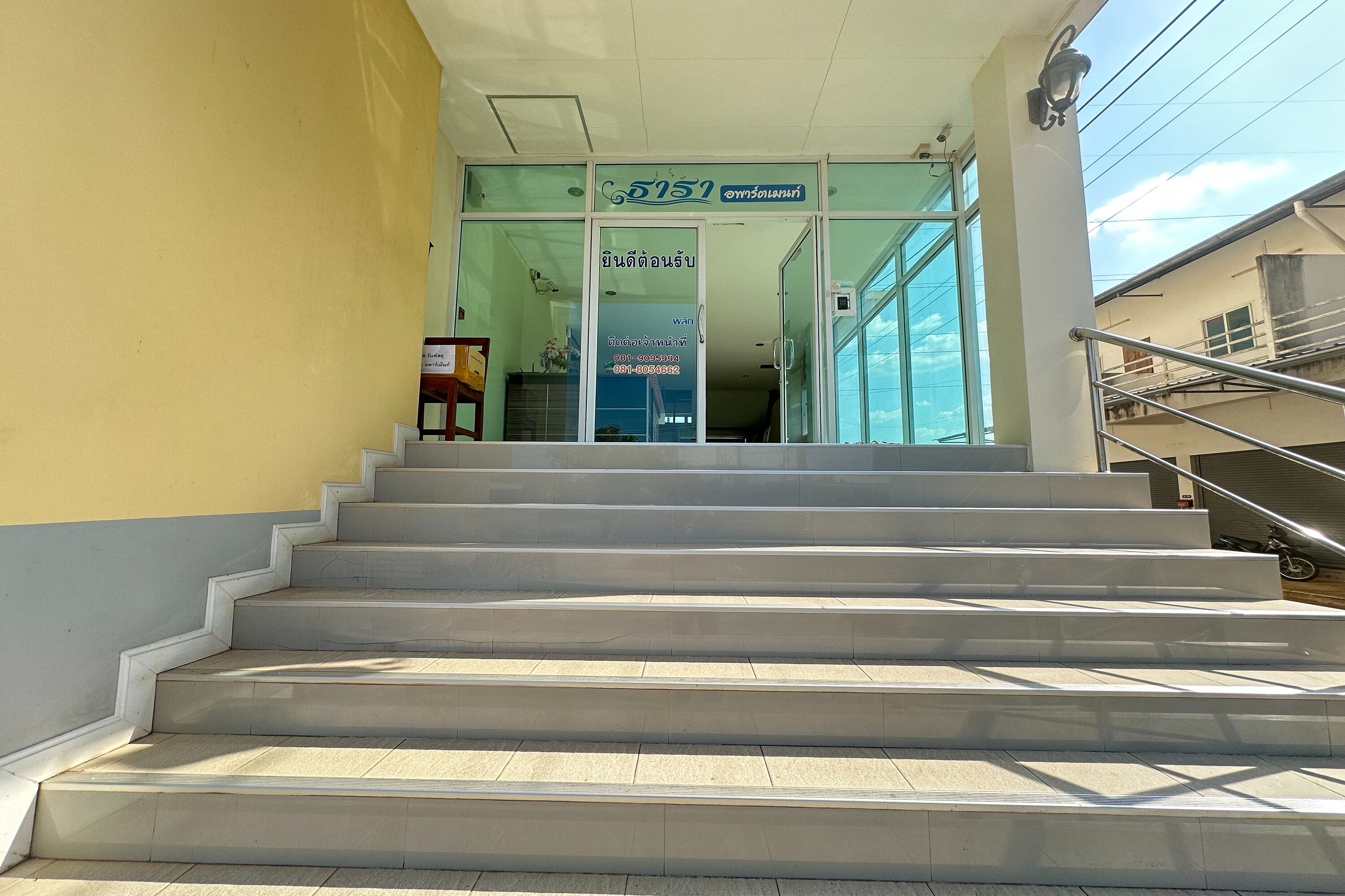 Un escalier menant à un bâtiment doté d’une entrée en verre et d’une enseigne au-dessus.