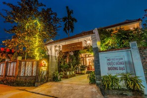 A hotel entrance with a signboard, a well-lit pathway, and lush greenery. - Trendy Life Villa Hoi An (Da Nang)
