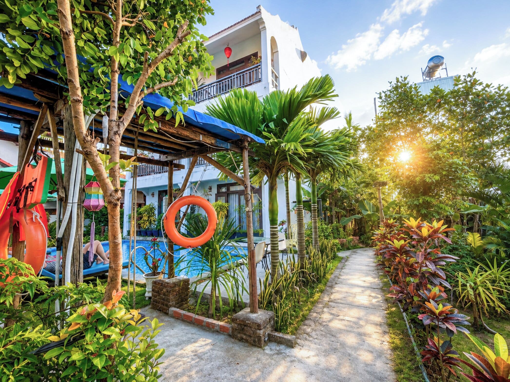 A tropical garden with a pool, a swing set, and a pathway.