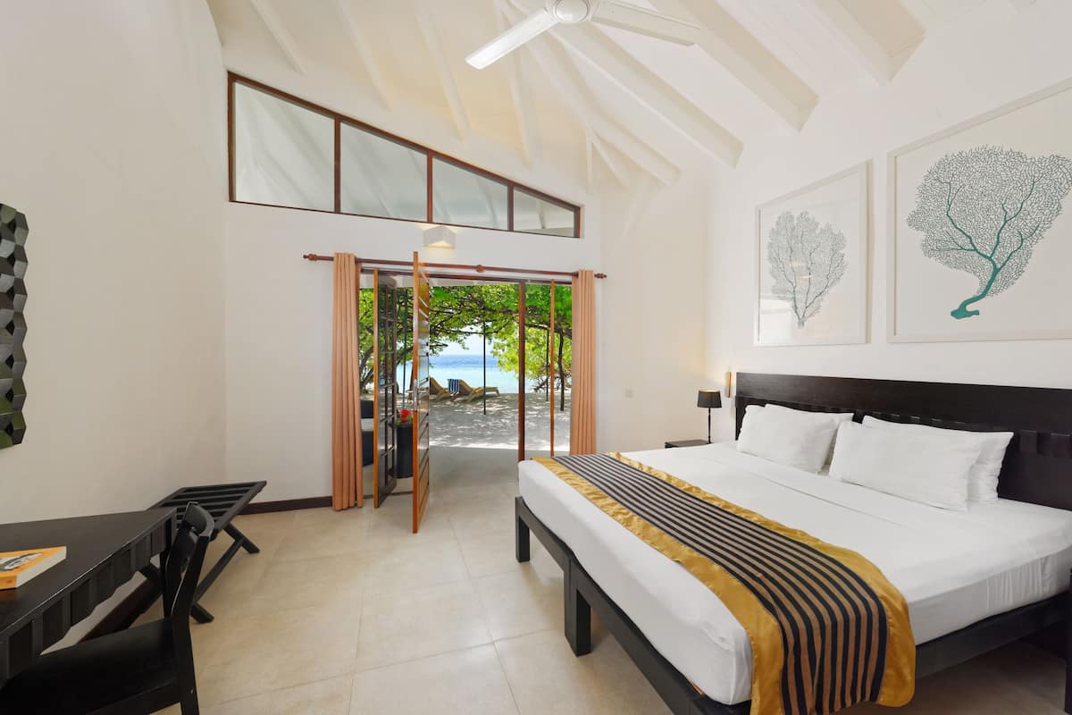 Habitación de hotel con cama, escritorio y vista al mar.