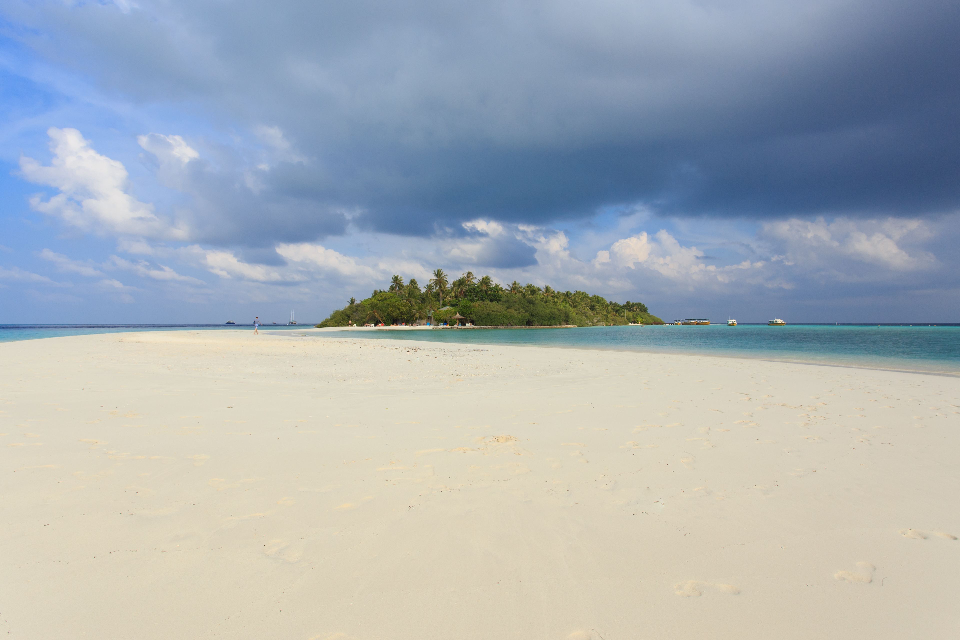 Una spiaggia con sabbia bianca e una piccola isola con alberi sullo sfondo.