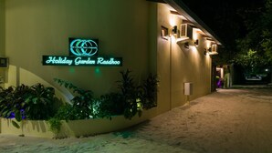 Un edifici amb un rètol de neó que diu "Holiday Garden Resort".