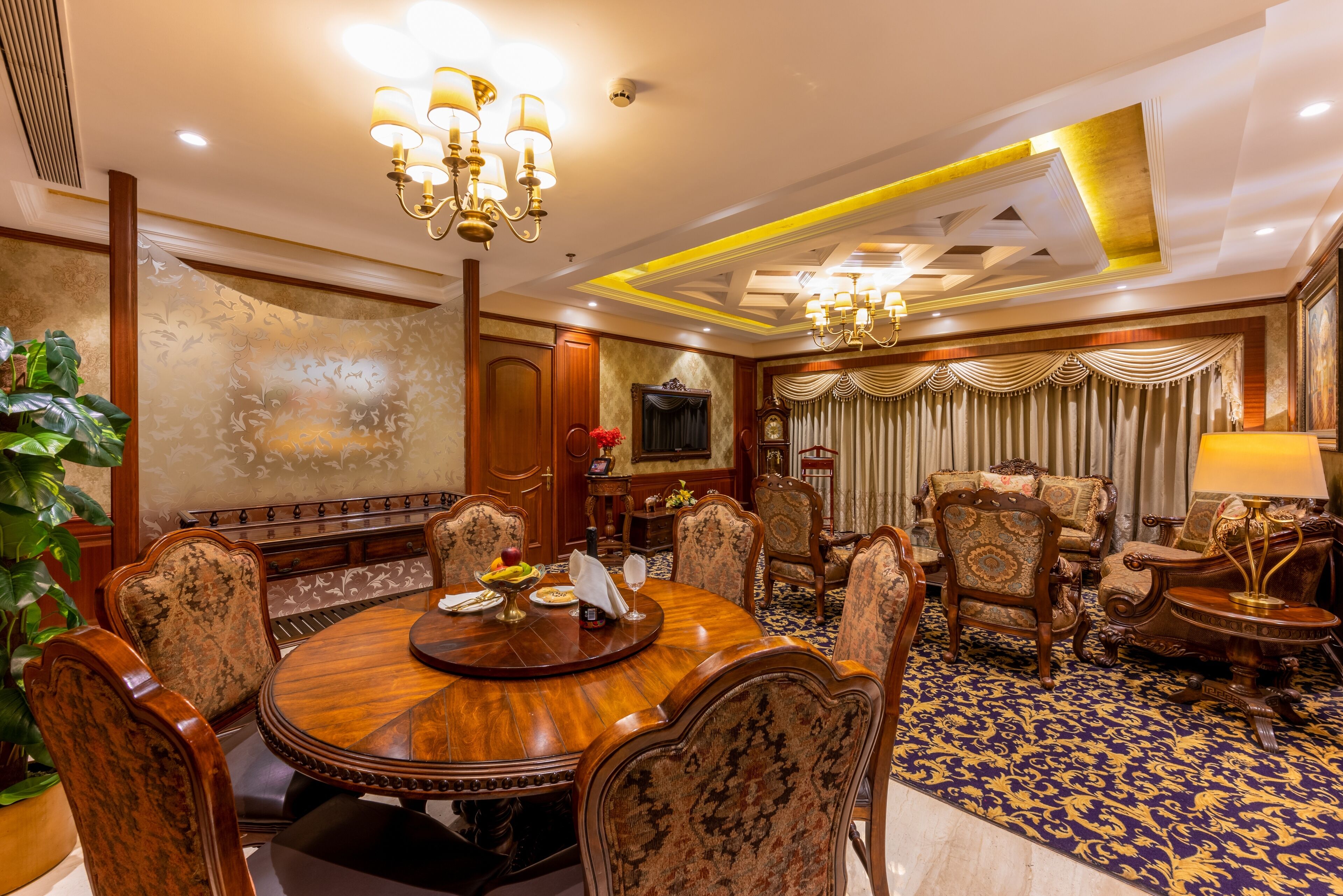 A formal dining room with a round wooden table, ornate chairs, and a chandelier.