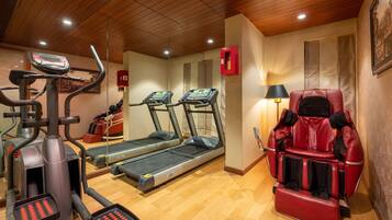 Un gimnasio con cintas de correr, una bicicleta estática y una silla de masajes.
