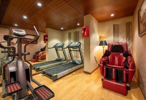 Un gimnasio con cintas de correr, una bicicleta estática y una silla de masajes.