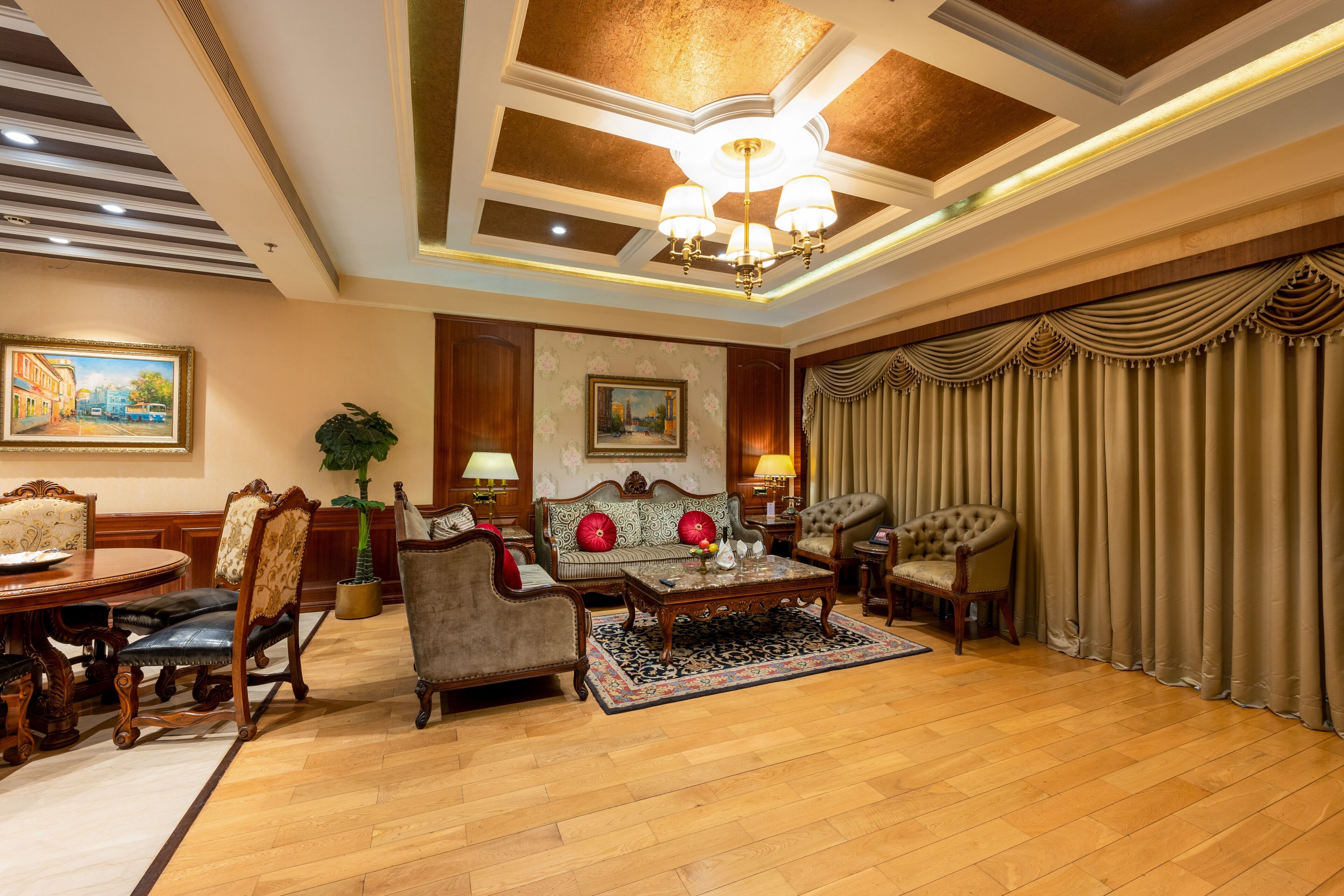 A spacious living room with a wooden floor, a large chandelier, and a sofa set.