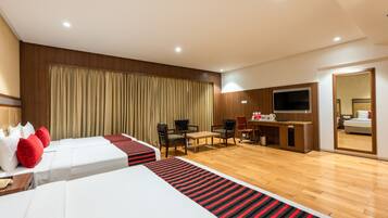 Habitación de hotel con dos camas, un escritorio, sillas, un televisor y un espejo.