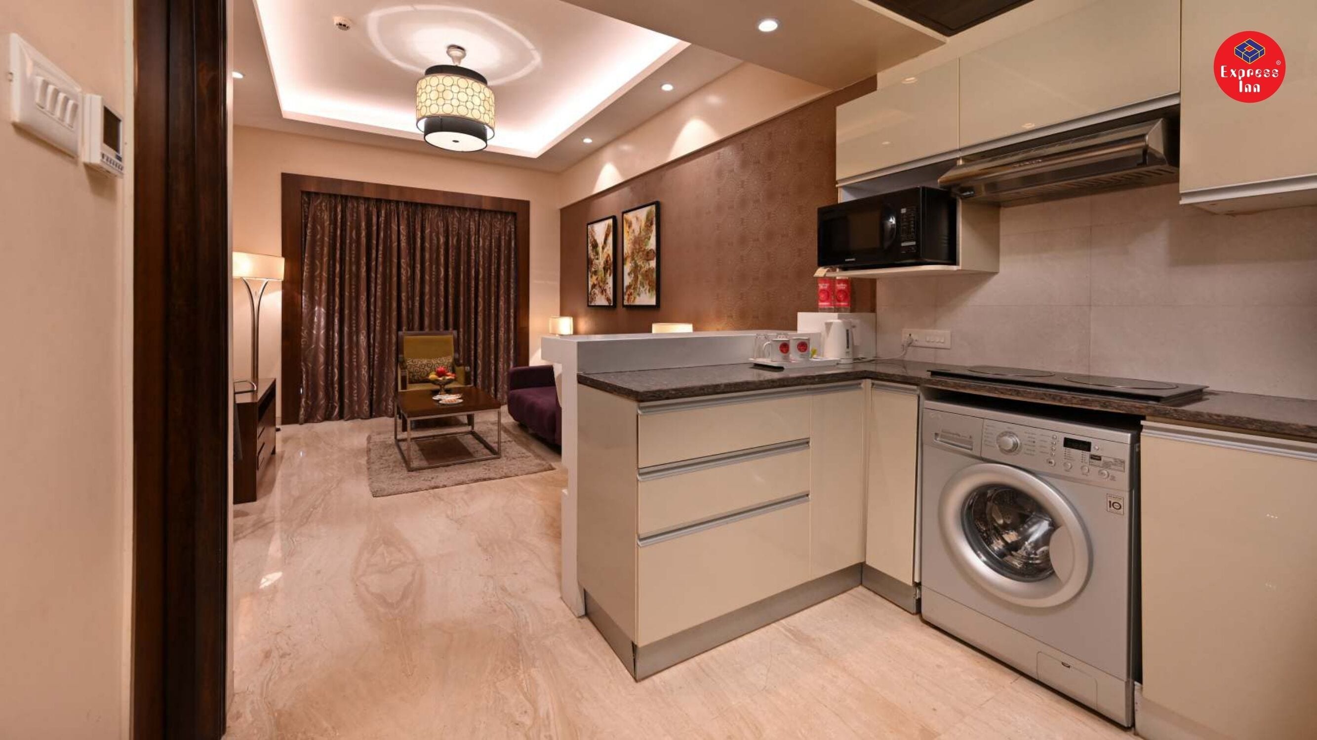 A compact kitchen with a washing machine, a microwave, and a small dining area with a table and chairs.