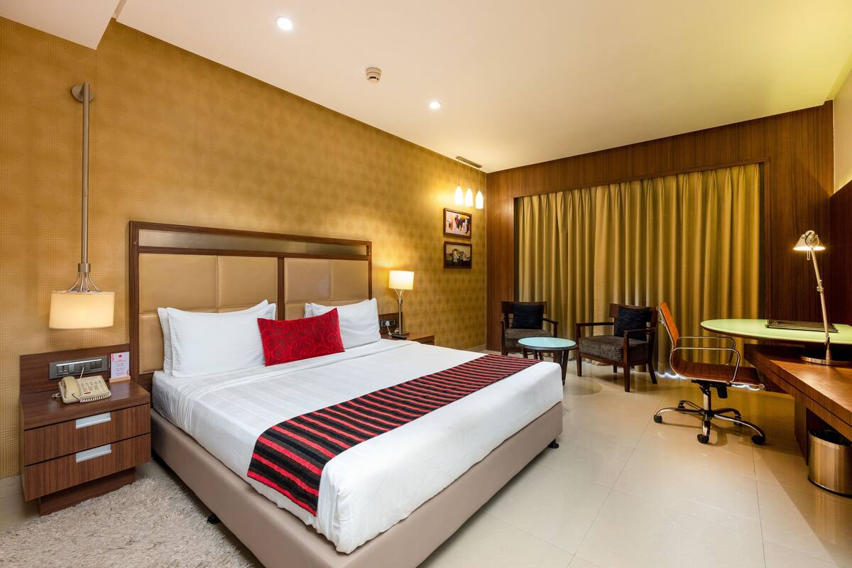 A hotel room with a large bed, bedside tables, a desk, and a chair.
