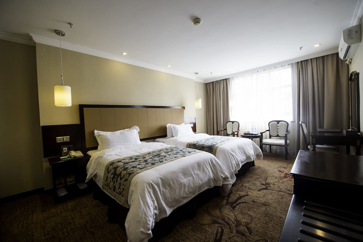 Een hotelkamer met twee bedden, een bureau, een stoel en een piano.