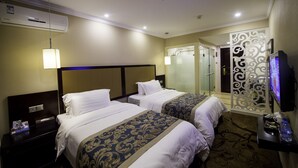 Une chambre d’hôtel avec deux lits, une télévision, un climatiseur et un élément de séparation décoratif.