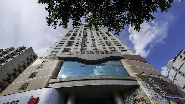 Un immeuble de grande hauteur doté d’une architecture moderne, avec une entrée imposante caractérisée par des portes en verre et une grande enseigne au-dessus de l’entrée.