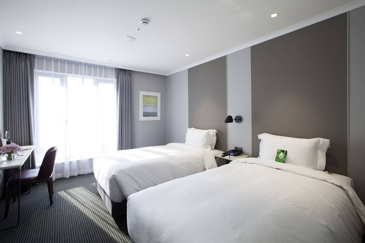 A hotel room with two beds, a desk, and a chair.