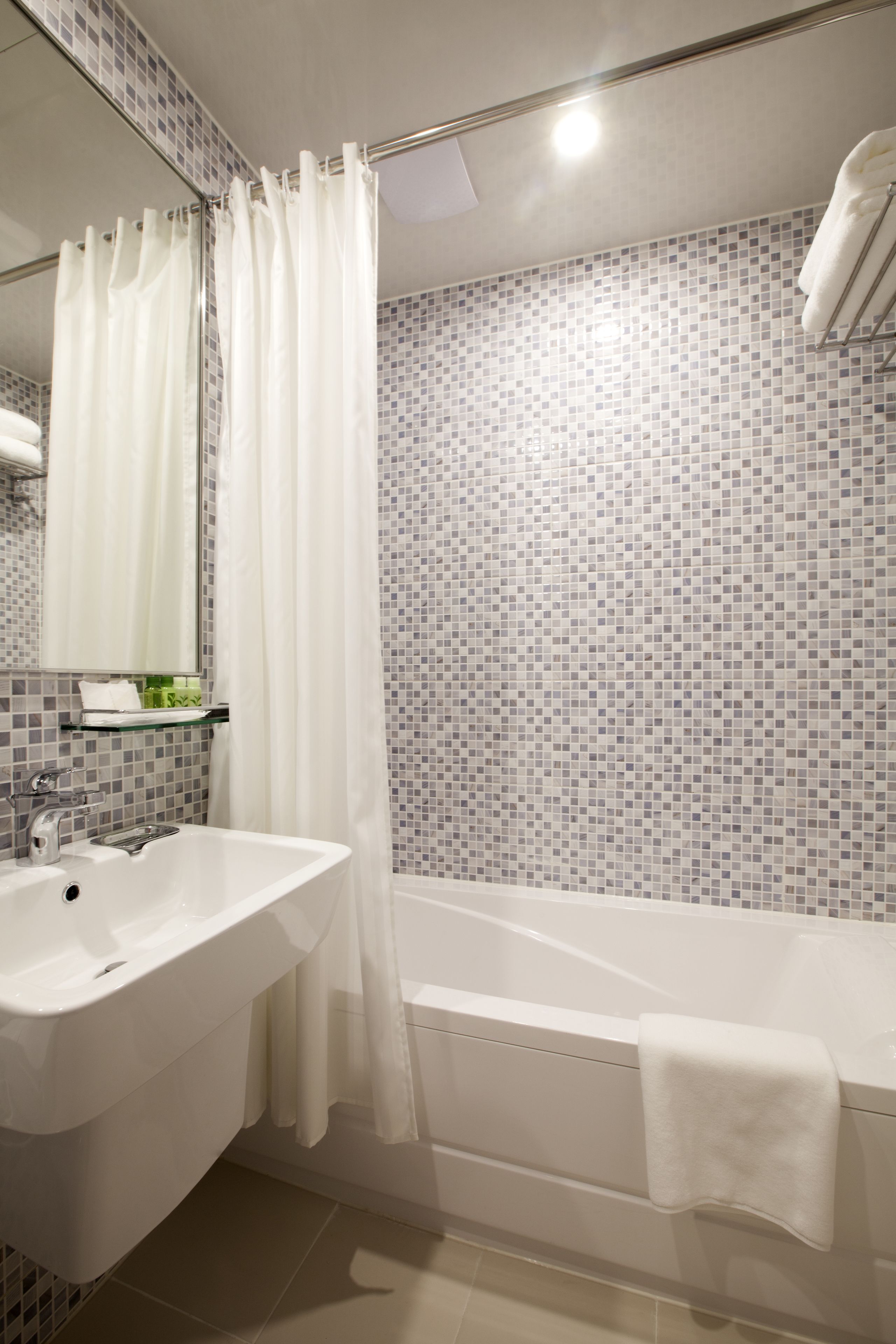 Un baño moderno con lavabo blanco, bañera y cortina de ducha.