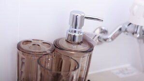 A bathroom with a glass soap dispenser and a faucet. - Place Iine (Tokyo)