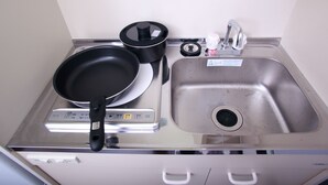 A kitchen with a stainless steel sink, a stove with a pan, a pot, and a faucet. - Place Iine (Tokyo)
