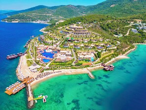 An aerial view of a coastal resort with multiple buildings, a marina, and a beach. - The Plaza Bodrum (Bodrum)