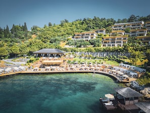 Un resort con área de piscina, sillas de descanso y una estructura de techo de paja.