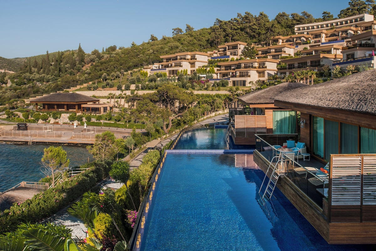 A resort with a swimming pool, wooden deck, and hillside villas.