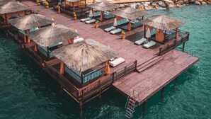 An overwater bungalows with thatched roofs, wooden walkways, and a pool area.
